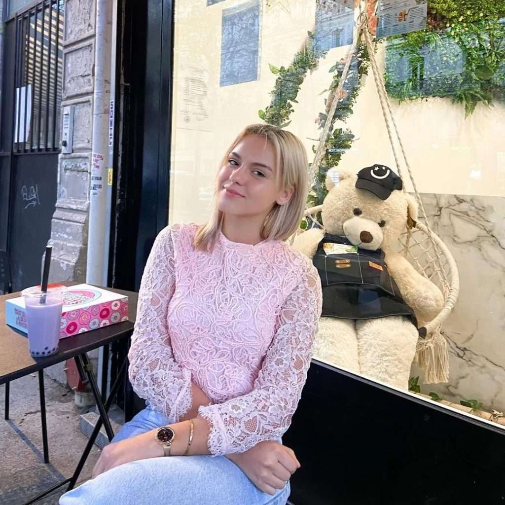Shannah Lindh wearing a stylish pink shirt, sitting comfortably on a black sofa | Fashion and Lifestyle Blogger